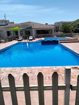 a large blue swimming pool next to a fence at Hermanus Beach Club Penthouse in Hermanus
