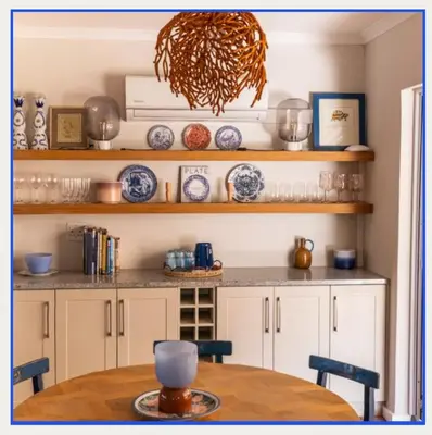 a kitchen with a table and a shelf with dishes at Kerala Cottage - farm charm inspired self-catering