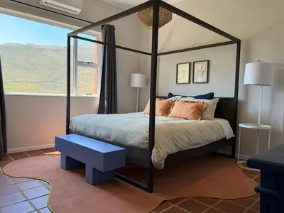 a bedroom with a four poster bed and a window at Kerala Cottage - farm charm inspired self-catering