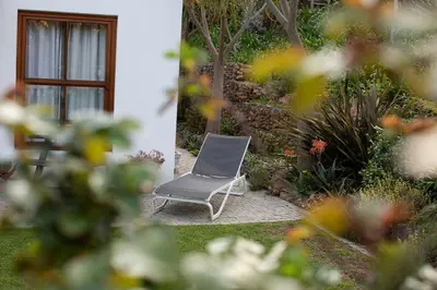 a chair sitting in a garden next to a building at Swan Cottage in Kylemore