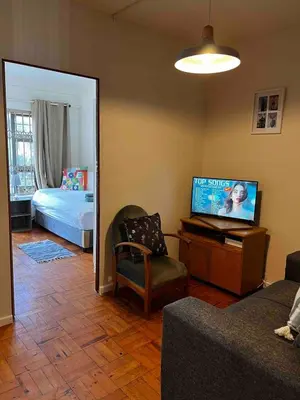 a living room with a tv and a bed and a mirror at Newly renovated Stellies 2 Bed apt in heart of Stellies! in Stellenbosch