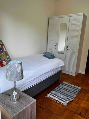 a bedroom with a bed and a table with a lamp at Newly renovated Stellies 2 Bed apt in heart of Stellies! in Stellenbosch