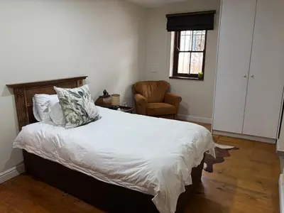 a bedroom with a bed with a chair and a window at Heldeberg 6 in Stellenbosch