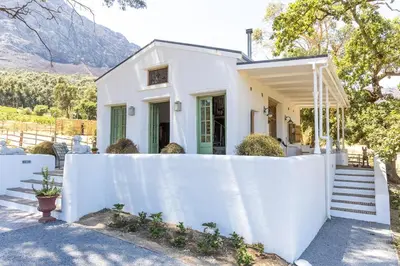 a white house with a white fence at Authentic and Charming French-inspired Cottage in Franschhoek