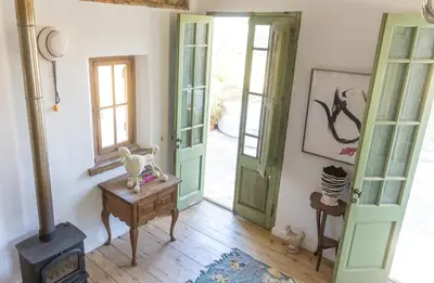 a room with a green door and a wood stove at Authentic and Charming French-inspired Cottage in Franschhoek