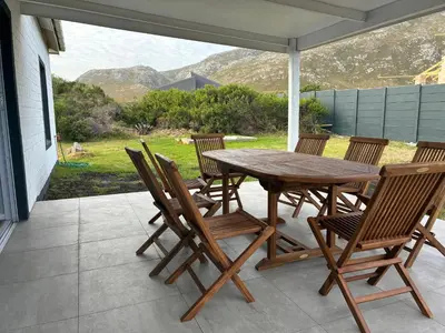 a wooden table and chairs on a patio at Silversands Serenity in Bettyʼs Bay