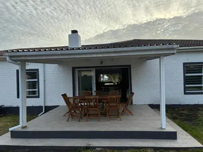 a patio with a table and chairs on it at Silversands Serenity in Bettyʼs Bay