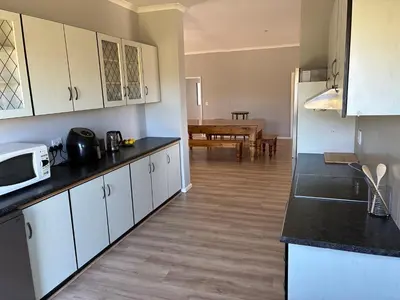 a kitchen with white cabinets and a dining room at Silversands Serenity in Bettyʼs Bay