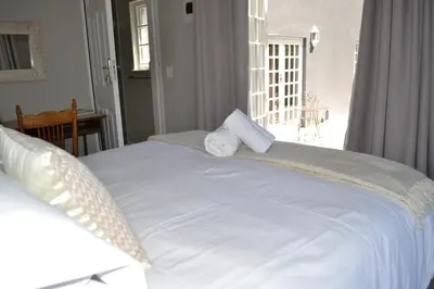 a large white bed in a room with a window at The Garden Shed Guest House in Wellington