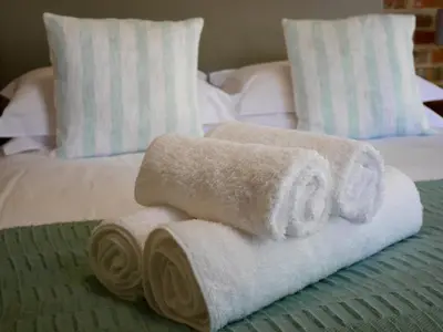 a pile of towels sitting on top of a bed at The Garden Shed Guest House in Wellington