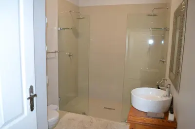 a bathroom with a sink and a glass shower at The Garden Shed Guest House in Wellington
