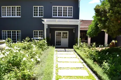 a blue house with a walkway in front of it at The Garden Shed Guest House in Wellington