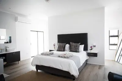 a white bedroom with a large bed with two pillows at MontMartre Chalets & Venue in Franschhoek