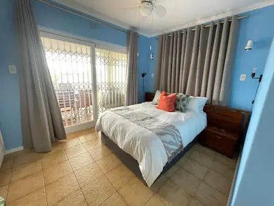 a blue bedroom with a bed and a window at Salty Leaves in Hermanus