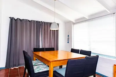 a dining room with a wooden table and chairs at Bagatelle in Pringle Bay