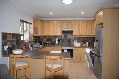 a kitchen with wooden cabinets and a table and chairs at 2-Bedroom Private Garden Flat, Durbanville in Durbanville