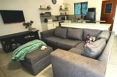a living room with a couch and a chair and a tv at Bed and Biscuits in Windmeul