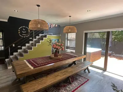 a dining room with a table and a staircase at Chasing Sunsets sea and mountain views in Hermanus