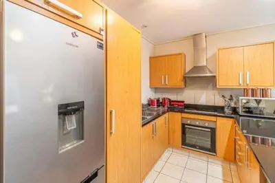 a kitchen with wooden cabinets and a refrigerator at Ezey Tours-Manhattan Suites in Cape Town