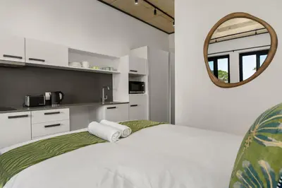 a white bedroom with a bed and a mirror at Bridgewater One 206 in Cape Town