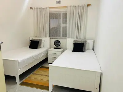 two white beds in a room with a window at Gorgeous beachfront hideout Strand beachfront in Strand