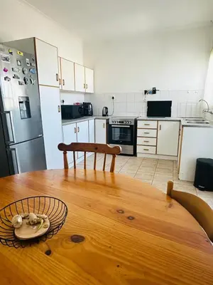 a kitchen with a wooden table and a kitchen with a refrigerator at Gorgeous beachfront hideout Strand beachfront in Strand