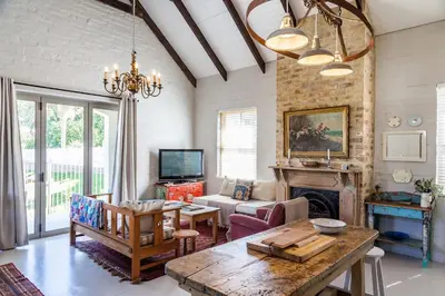 a living room with a table and a fireplace at Nerf-af Cottage at Onrus, Hermanus in Hermanus