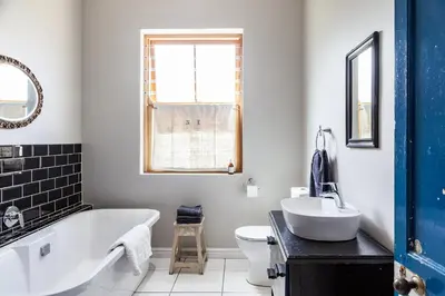a bathroom with a tub and a toilet and a sink at Nerf-af Cottage at Onrus, Hermanus in Hermanus