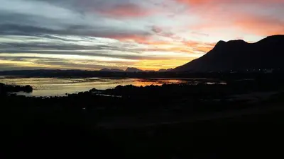 a sunset over a river with a mountain in the background at Nerf-af Cottage at Onrus, Hermanus in Hermanus