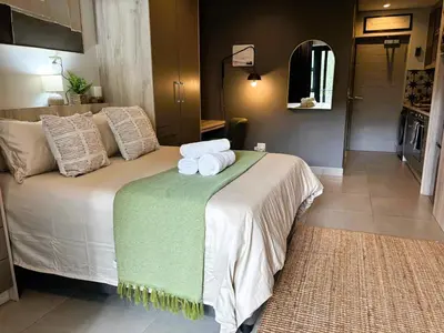 a bedroom with a bed with towels on it at Bachelors Unit at The Den in Stellenbosch