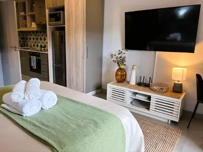 a bedroom with a bed with a flat screen tv at Bachelors Unit at The Den in Stellenbosch