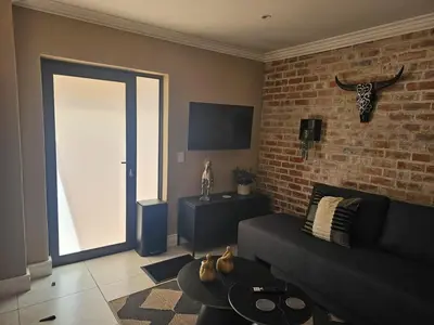 a living room with a couch and a brick wall at Cape Town Glam in Welgemoed