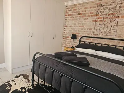 a black bed in a room with a brick wall at Cape Town Glam in Welgemoed