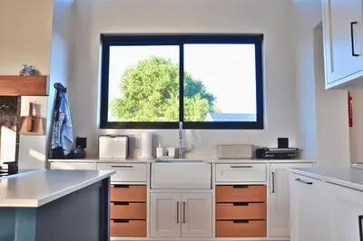 a kitchen with white cabinets and a window at Modern 4BDR Flaming Bay in Hermanus in Hermanus