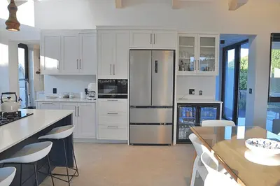 a kitchen with white cabinets and a table and a refrigerator at Modern 4BDR Flaming Bay in Hermanus in Hermanus