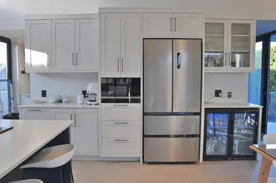 a kitchen with white cabinets and a stainless steel refrigerator at Modern 4BDR Flaming Bay in Hermanus in Hermanus