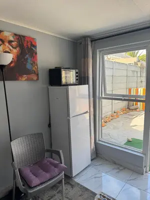 a kitchen with a refrigerator and a chair and a window at Legacy lodge in Goodwood