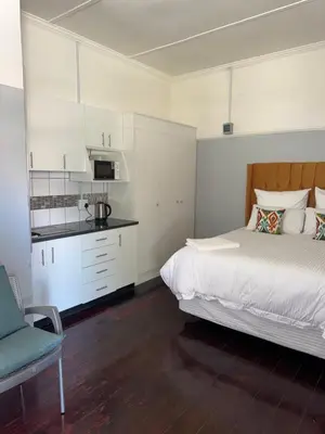 a bedroom with a large bed and a kitchen at Legacy lodge in Goodwood