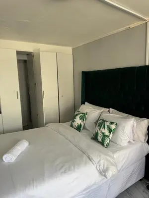 a large white bed with green and white pillows at Legacy lodge in Goodwood