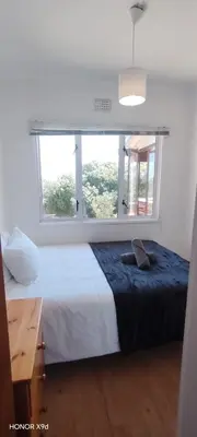 a bedroom with a large bed and a window at Pet Friendly Sandbaai in Hermanus