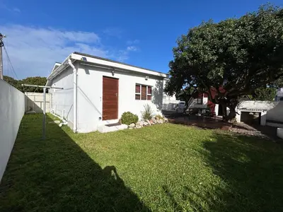 a small white house with a grass yard at Protea Escape - Apartment in Hermanus