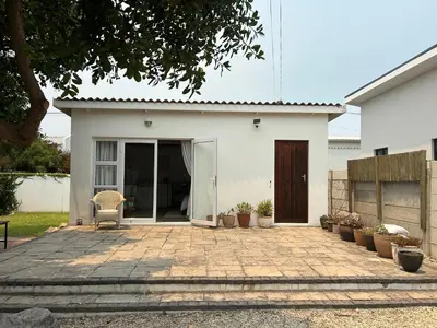 a white house with a patio in front of it at Protea Escape - Apartment in Hermanus
