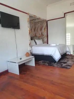 a bedroom with a bed and a flat screen tv at Ludinz Self Catering Guest House