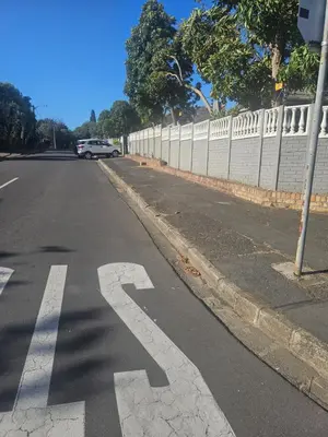 an empty street with a white fence and a car at Ludinz Self Catering Guest House