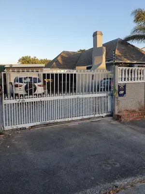 a white fence in front of a house at Ludinz Self Catering Guest House