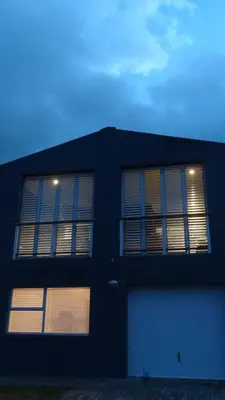 a black building with two windows and a garage at Pringle Beach House in Pringle Bay