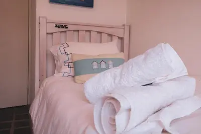 a bed with white sheets and towels on it at Pringle Beach House in Pringle Bay