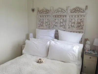 a white bed with a teddy bear sitting on top of it at Pringle Beach House in Pringle Bay