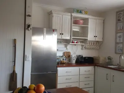 a kitchen with a stainless steel refrigerator and white cabinets at Pringle Beach House in Pringle Bay