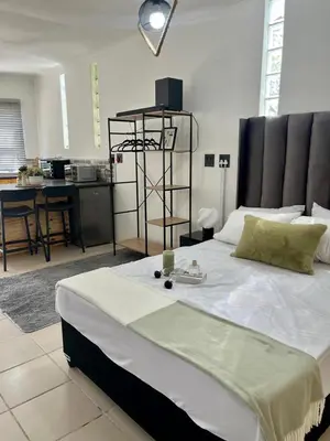 a bedroom with a large bed and a kitchen at Angel's Cottage in Paarl